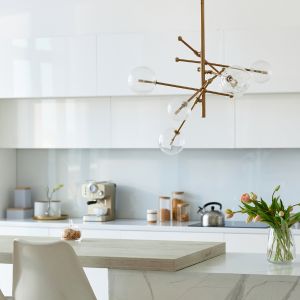 Visuel décoratif de la cuisine d'une maison neuve, disposant d'un bar sur lequel est apposé une calculatrice et documents immobiliers représentant les frais cachés d’un achat immobilier.