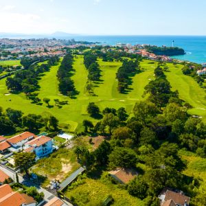 Vue panoramique d’un terrain constructible au Pays Basque avec collines et océan en arrière-plan