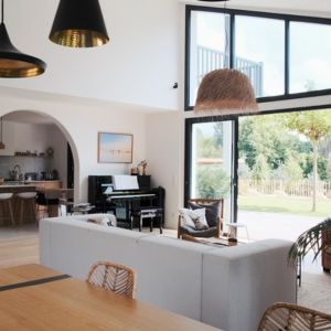 Photographie d’une villa moderne au Pays basque, avec terrasse bois et grandes baies vitrées, symbole d’un projet sur mesure réussi.