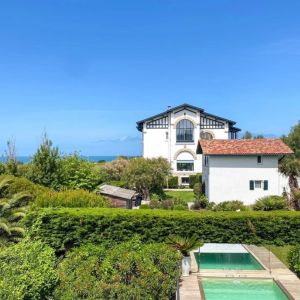Maison neuve basque à Bidart avec façade blanche et toit rouge, surplombant l’océan Atlantique.